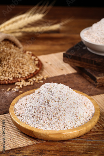 Whole wheat flour and grains on rustic wooden table - fresh baking ingredients for healthy bread making