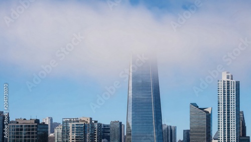 Skyscraper top obscured by a layer of stratospheric clouds. 