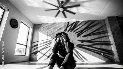 Woman Suffering From Anxiety Sitting in a Room With Harsh Sunlight and Shadows