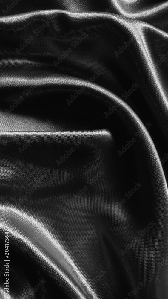 Fototapeta premium Luxurious black satin fabric flows with elegant folds, creating a sleek and sophisticated texture full of depth and shine.