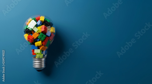 Bright light bulb filled with colorful building toy bricks symbolizing creative ideas, innovative thinking, and the spark of new concepts for business development and problem-solving