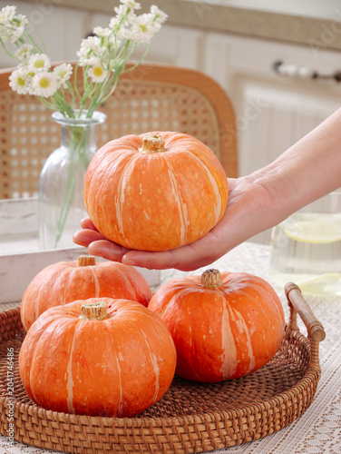 Fresh Orange Pumpkins in Kitchen Display with Hand Holding Seasonal Harvest Produce
