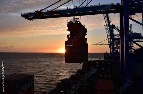 Containerschiff wird bei Sonnenuntergang im Hafen Bremerhaven entladen