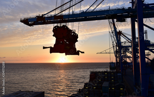 Containerschiff wird bei Sonnenuntergang im Hafen Bremerhaven entladen