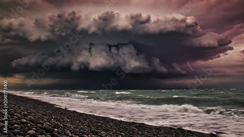 Dramatic Coastal Storm with Lightning Strikes Over the Ocean and Waves Crashing onto the Pebble Beach under Thunderclouds