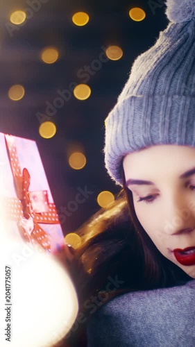 Young woman check the Christmas present box hearing what is inside
