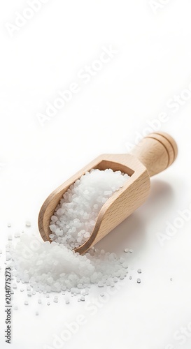Coarse White Sea Salt Spilling From Wooden Scoop on Clean White Surface