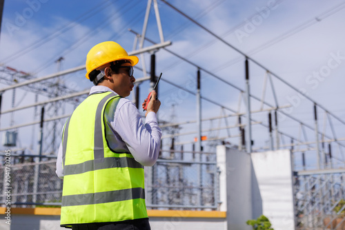 Engineer communicating with radio at power plant substation