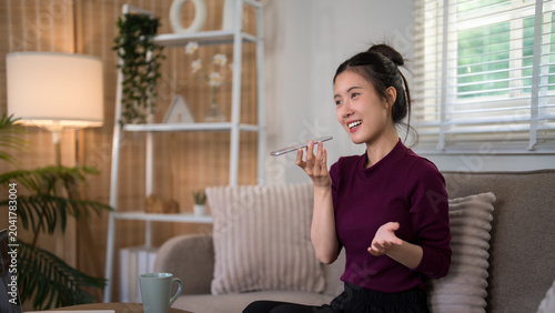 Картината върху платно Asian woman using voice assistant smartphone technology hands free device speaki