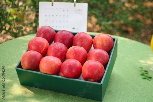 Fresh Red Apples in Box on Green Table Outdoors - Healthy Organic Fruit Display
