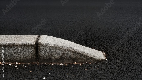 Close Up of a Concrete Curb in the Rain with Wet Asphalt Surface