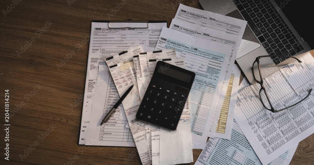 Fototapeta premium Tax forms, receipts, and calculator arranged on a desk with financial documents and laptop, supporting tax preparation, accounting review, expense calculation, and tax filing workflow.