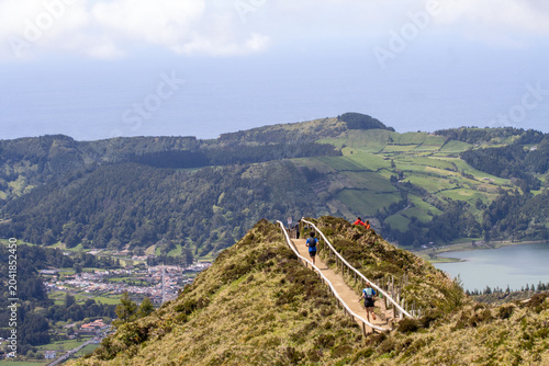 Hiking trail on a mountain ridge overlooking rolling green countryside and a lake