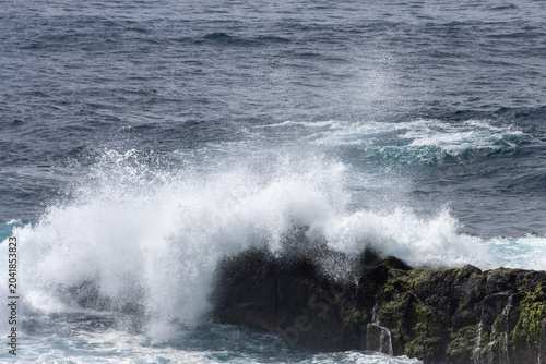 Ocean waves crashing against a rocky shoreline with sea spray