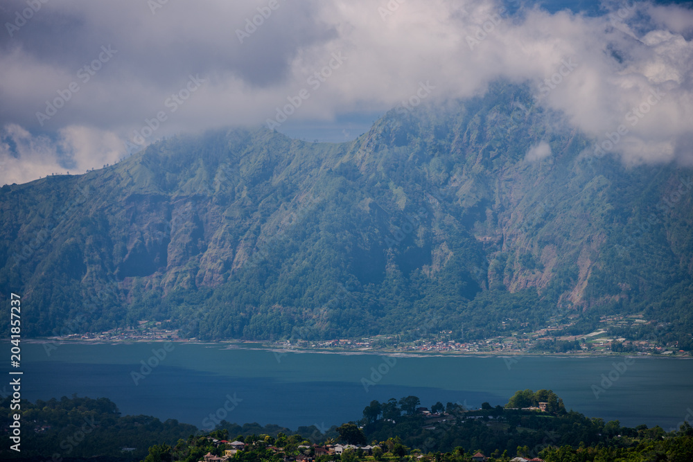Obraz premium Mount Batur caldera wall rising above the blue waters of Lake Batur in Kintamani