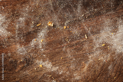 Flour dusting and bread crumbs scattered on a rustic dark wooden cutting board