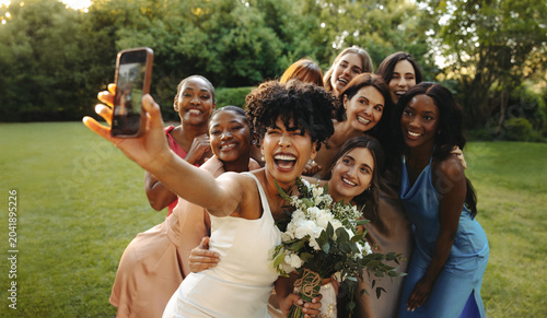 Bride and bridesmaids taking a celebratory selfie outdoors
