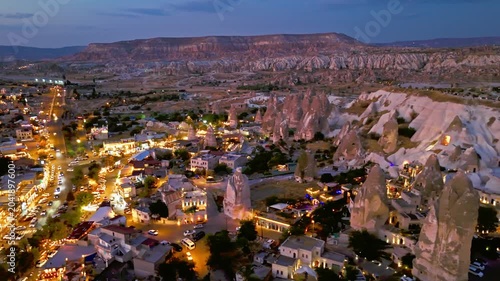 Drone view of Goreme, Cappadocia, Turkey at night. Cave houses, rocky hills and glowing streets show a peaceful evening panorama.