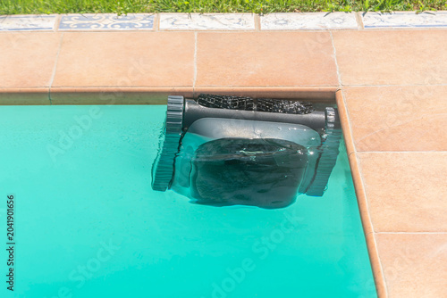 Photos A cordless robot is cleaning the edge of an in-ground pool