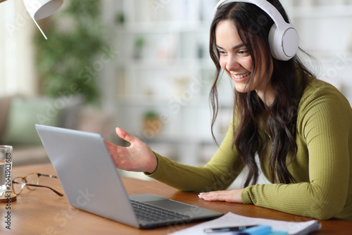 Happy young student with headphone making video call at home