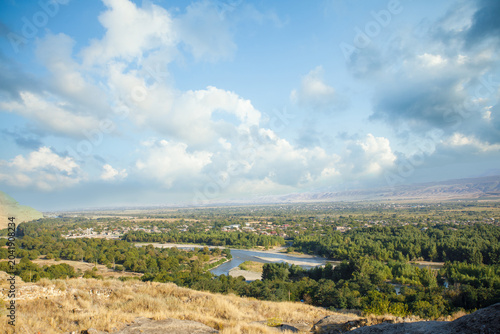 Canvastavla River Mtkvari near Uplistsikhe Cave Town-Fortress against blue sky with white cl