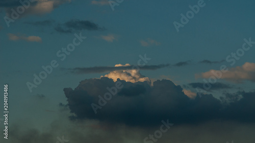 Dark gray rain clouds and a white cloud in the evening sky banner.