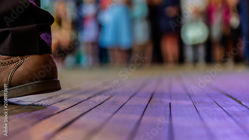 Fragment of mens shoes on a wooden floor in a dance studio with blurred silhouettes of people banner.
