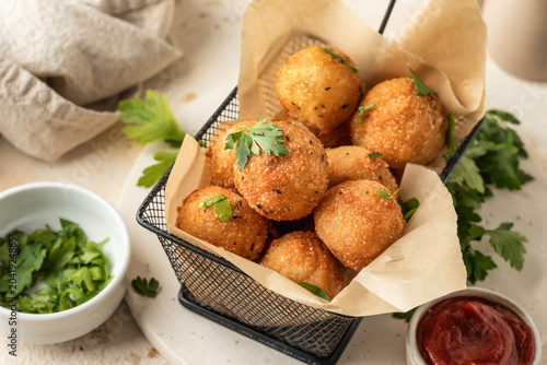 Foto Golden fried cheesy balls with a gooey cheese center served with fresh parsley leaves garnish and sause