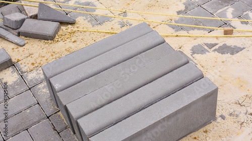 Obraz na płótnie A row of grey concrete border stones stands on a sandy construction site during