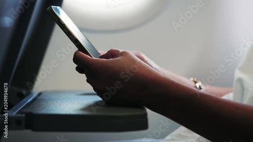 Businesswoman using a smartphone during flight on airplane tray table