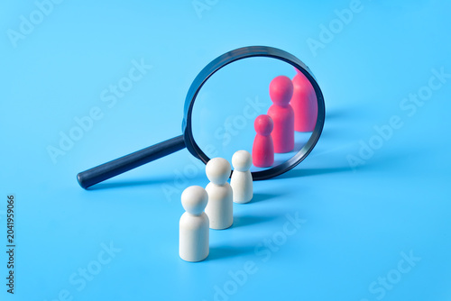 White wooden figures row with Magnifying glass and red wooden figures.