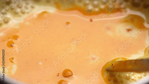 Macro video of turmeric powder being poured into plant based rice beverage during preparation of homemade golden milk