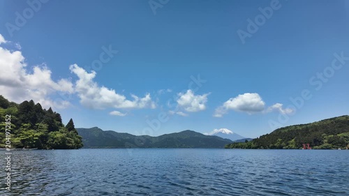 Timelapse of a lake in Hakone, Japan with shrine and Mount Fuji in background on beautiful sunny day