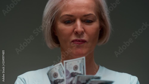 Old Caucasian woman counts the cash one hundred in hands, banknotes. Senior female holds paper money USD dollars in palms, with money deficit. Utility Bills Payment earnings. Elderly lady counting.