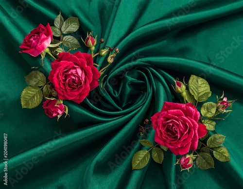 Vibrant Pink Roses Arranged on Swirled Emerald Satin Fabric Background