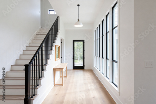 Bright modern hallway with large windows, staircase, and wooden console table