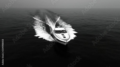 Luxurious white motorboat cruising swiftly across dark ocean waters generating foamy wakes on an overcast day