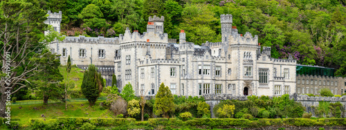 Bild auf Leinwand Kylemore Abbey stands on Pollacappul Lough below Druchruach Mountain in Connemara, County Galway