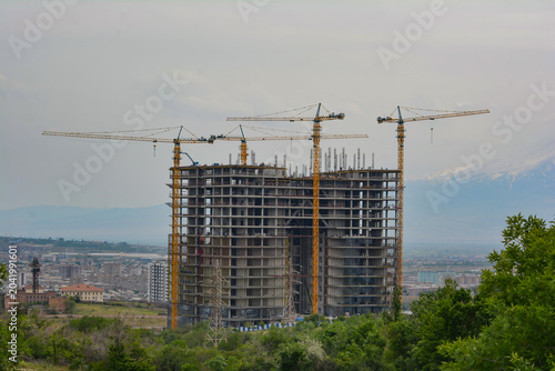 Construction of a new residential complex with cranes in the city. Construction of a multi-storey building with cranes in the background. Rise building in the city
