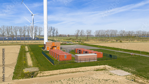 Aerial view of Energiepark Haringvliet Zuid with wind turbines, solar panels, and battery storage units under a blue sky in Stad aan 't Haringvliet, South Holland, Netherlands.