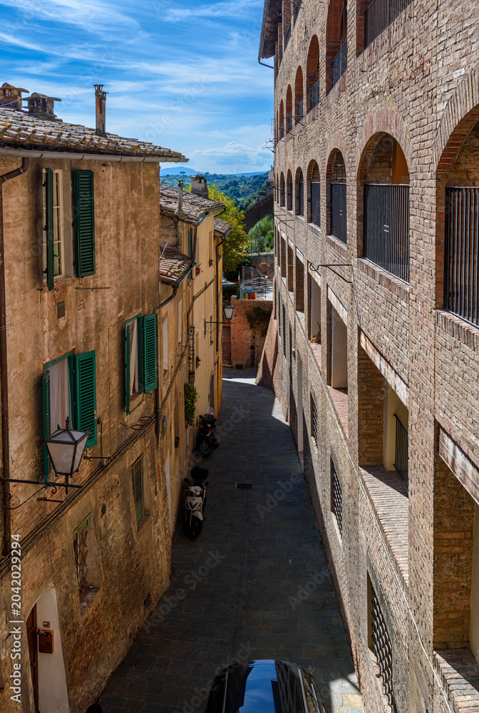 Naklejka premium Medieval narrow street in Siena, Tuscany, Italy. Architecture and landmark of Siena. Cozy cityscape of Siena