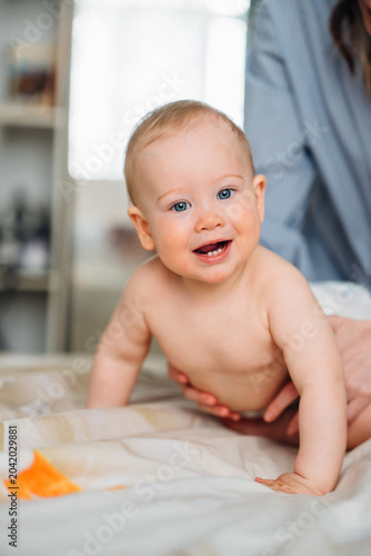Happy laughing baby showing first teeth with mother at home