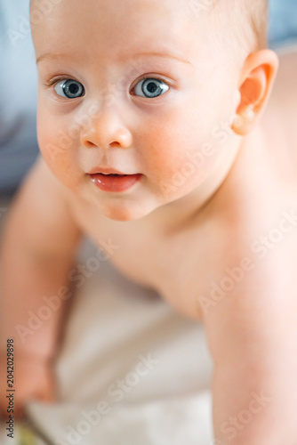 High angle portrait of a cute crawling baby with big blue eyes
