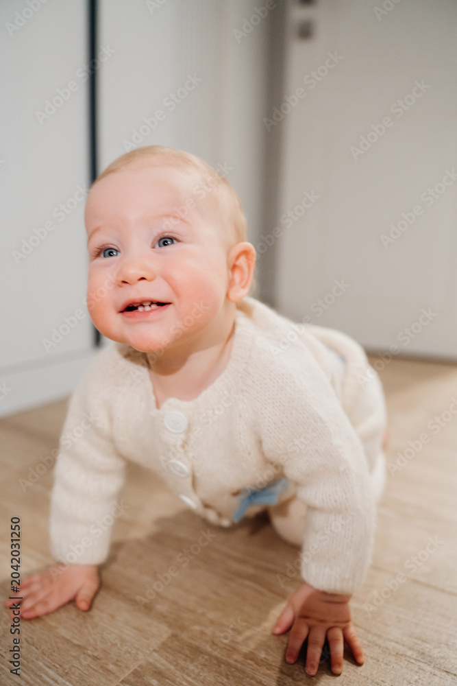 Fototapeta premium Happy Baby Crawling on Floor in Cozy Knitted Sweater