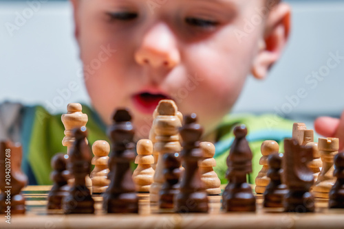 Foto Young child fascinated by chess pieces during an educational play session at home