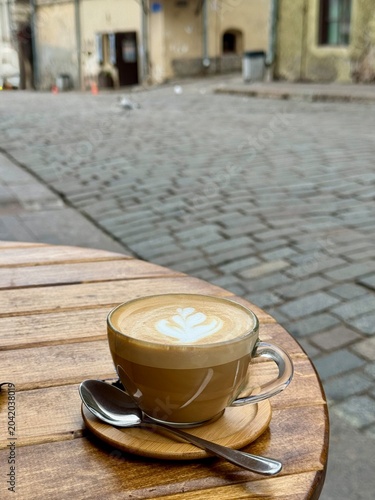    A cup of coffee with milk on a table in a street cafe. Selective focus