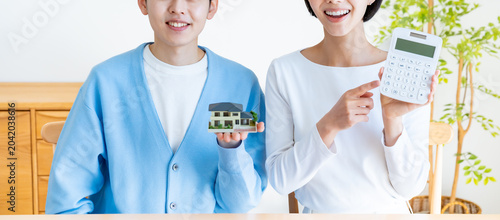 Foto 日本人カップルが家の模型と電卓を持って住宅購入を悩むシーン