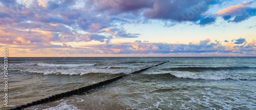 Bild auf Leinwand Panoramic sunset over the Baltic Sea with a traditional wooden groin in the wave