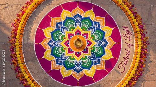 Beautiful colorful rangoli design with a lit diya lamp in the center for diwali festival celebration