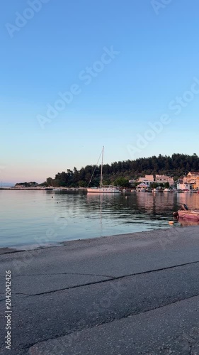 Golden orange sunset over a glassy calm sea, peaceful bay, mirror-like water, natural coastal landscape, serene evening atmosphere